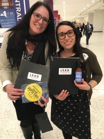 Two women stand holding folders saying "LEAD Legislative Education and Advocacy Day"